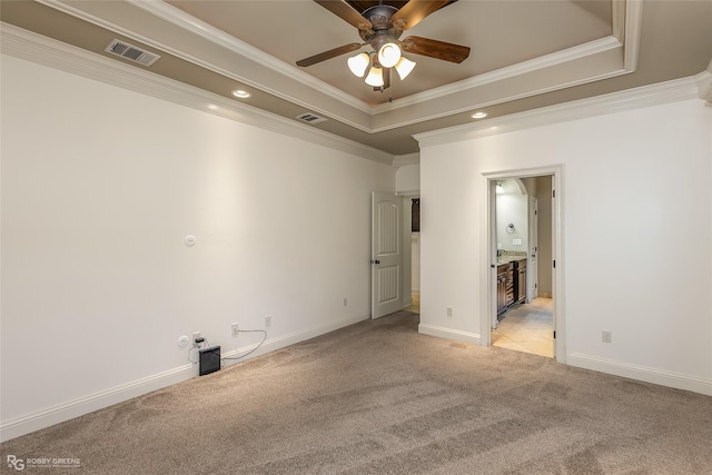 carpeted spare room with ceiling fan, ornamental molding, and a tray ceiling