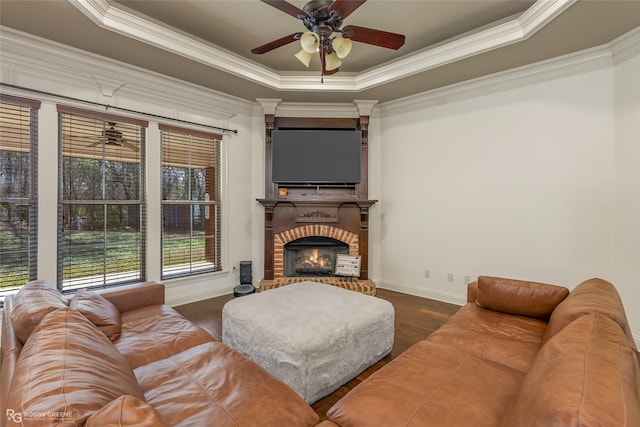 living room with dark hardwood / wood-style flooring, a brick fireplace, a tray ceiling, and crown molding