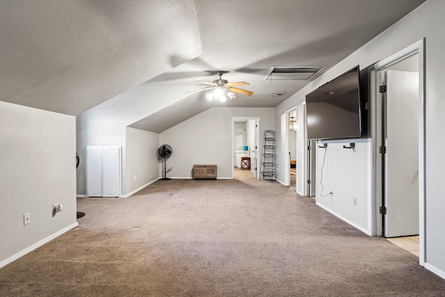 additional living space with ceiling fan, light colored carpet, lofted ceiling, and a textured ceiling