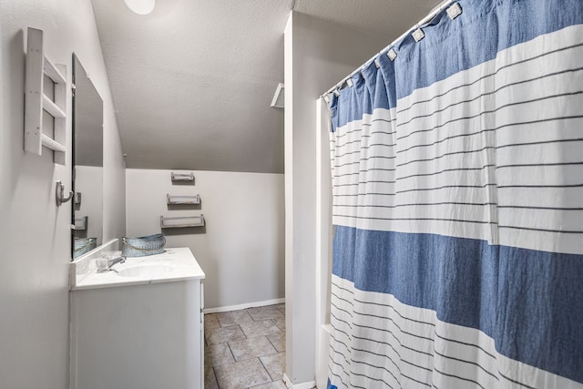 bathroom featuring a textured ceiling, vanity, and vaulted ceiling