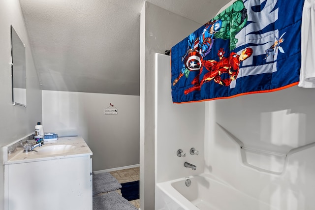 bathroom featuring a textured ceiling, lofted ceiling, vanity, and shower / bathtub combination