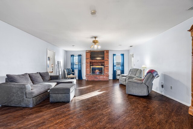 living room featuring dark hardwood / wood-style flooring and a brick fireplace