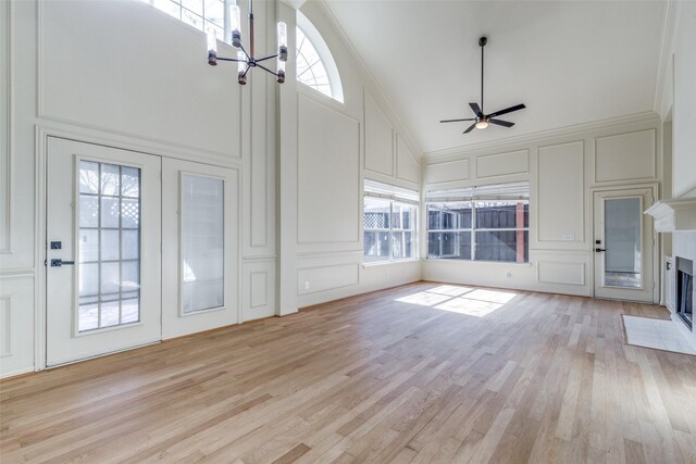 unfurnished dining area with a towering ceiling, a chandelier, and light hardwood / wood-style floors