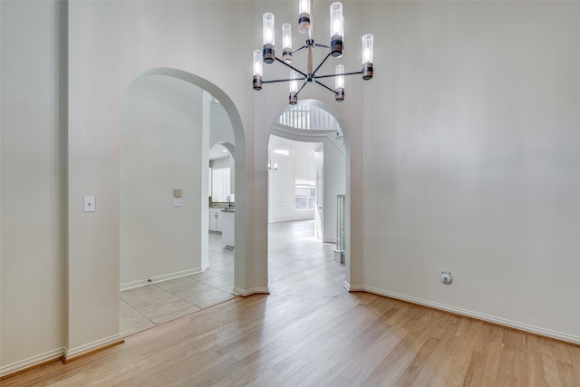 interior space featuring light wood-type flooring, an inviting chandelier, and a towering ceiling