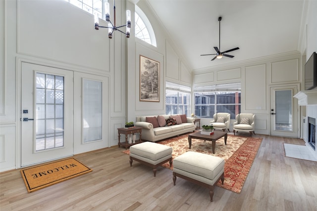 interior space featuring ceiling fan with notable chandelier, high vaulted ceiling, crown molding, and light hardwood / wood-style flooring