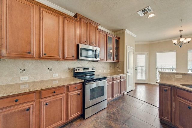 kitchen featuring appliances with stainless steel finishes, tasteful backsplash, a chandelier, hanging light fixtures, and ornamental molding