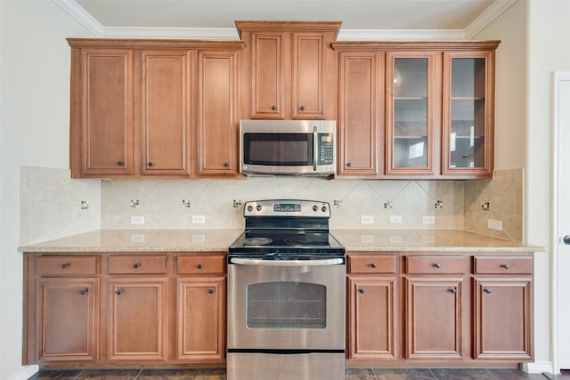 kitchen featuring light stone countertops, backsplash, ornamental molding, and stainless steel appliances