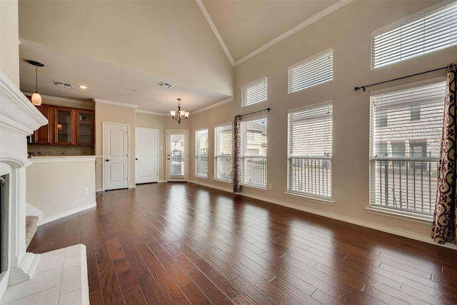 unfurnished living room featuring dark wood-type flooring, ornamental molding, high vaulted ceiling, and an inviting chandelier