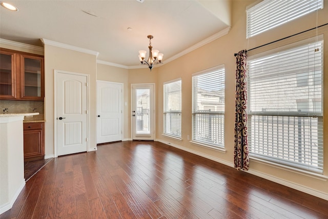 unfurnished dining area featuring dark wood-type flooring, ornamental molding, and an inviting chandelier