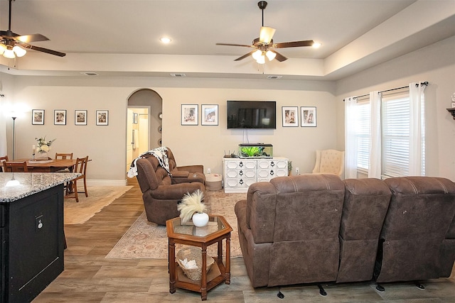 living room with a tray ceiling, ceiling fan, and hardwood / wood-style flooring