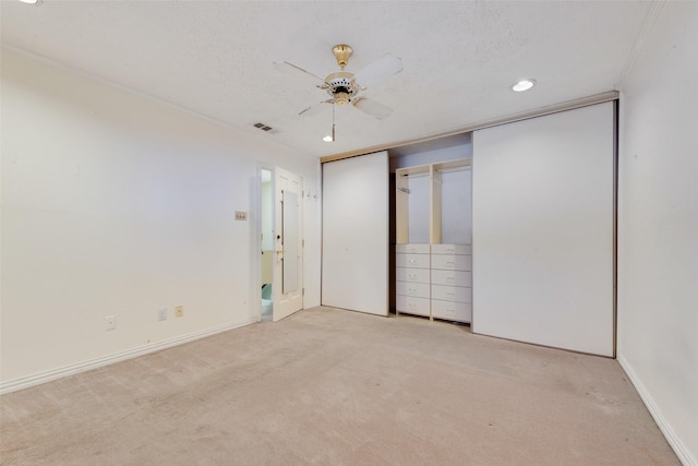 unfurnished bedroom with ceiling fan, light colored carpet, a textured ceiling, and a closet