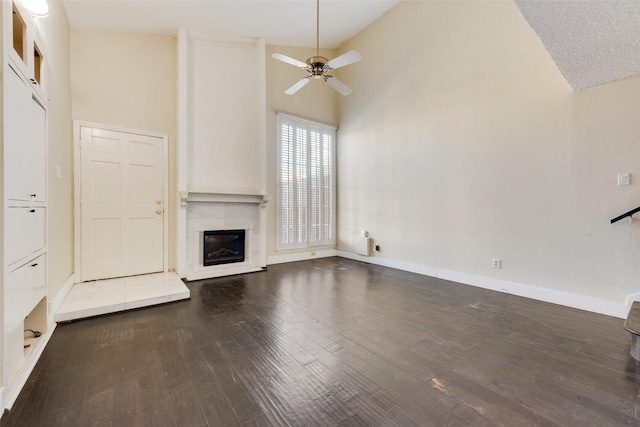 unfurnished living room with dark hardwood / wood-style flooring, high vaulted ceiling, ceiling fan, and a tiled fireplace