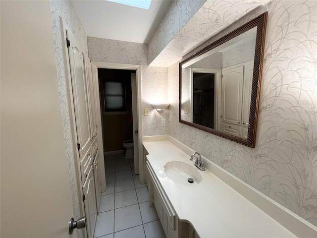 bathroom featuring tile patterned floors, vanity, toilet, and a skylight