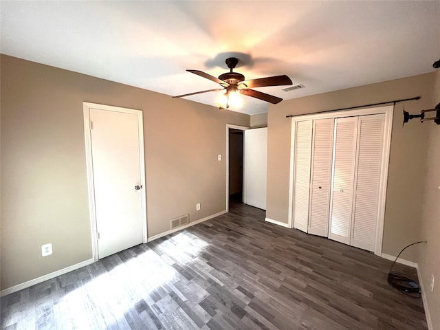 unfurnished bedroom with a closet, dark hardwood / wood-style floors, and ceiling fan