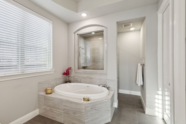 bathroom with tile patterned flooring and tiled tub