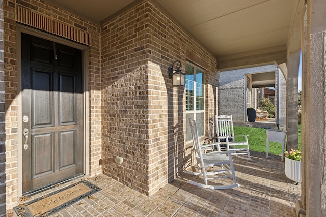 entrance to property featuring covered porch and brick siding