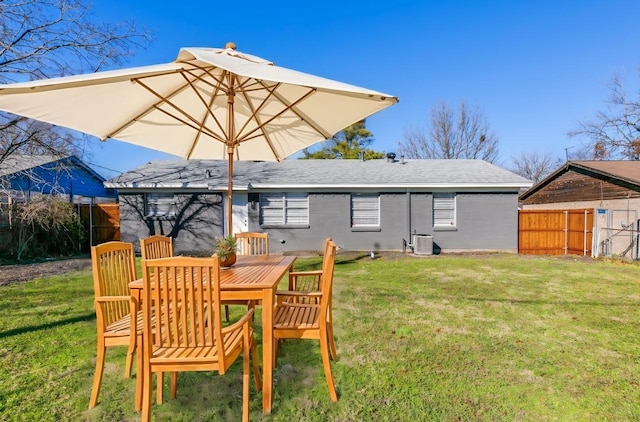 rear view of property featuring cooling unit and a lawn