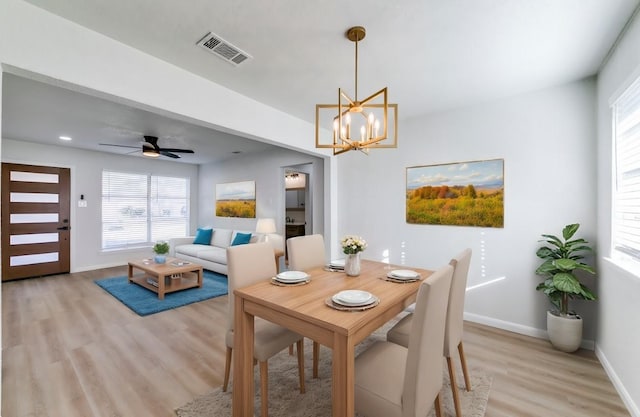 dining room featuring ceiling fan with notable chandelier and light hardwood / wood-style flooring