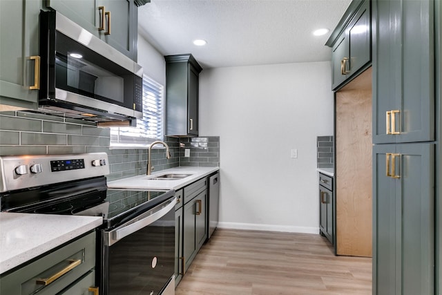 kitchen with sink, appliances with stainless steel finishes, tasteful backsplash, light stone counters, and light hardwood / wood-style floors