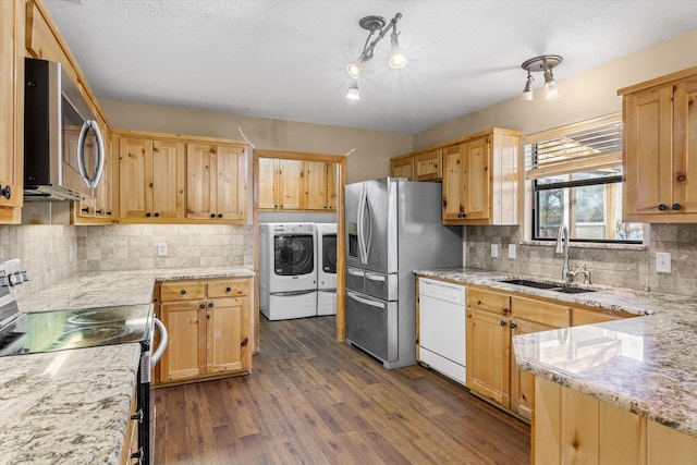 kitchen with light brown cabinets, a sink, washing machine and dryer, dark wood finished floors, and appliances with stainless steel finishes