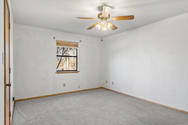 empty room with a textured ceiling, carpet, baseboards, and ceiling fan