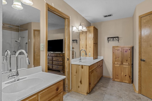 bathroom with two vanities, visible vents, a shower, and a sink