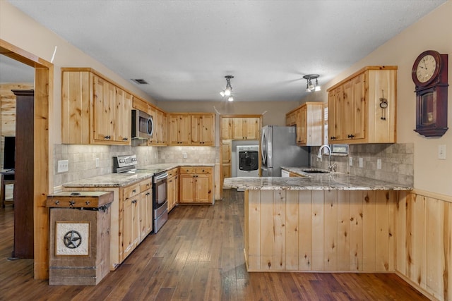 kitchen with light brown cabinetry, appliances with stainless steel finishes, a peninsula, washer / clothes dryer, and a sink