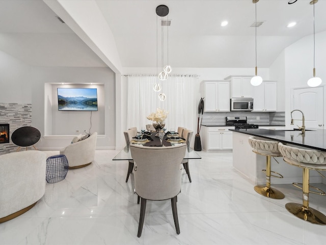 dining room with lofted ceiling, sink, and a fireplace