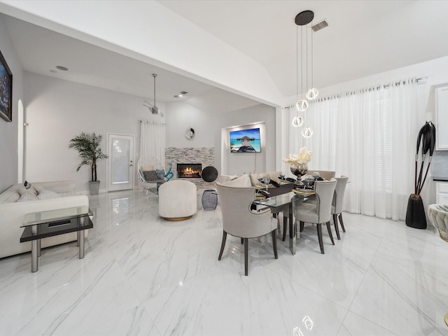 dining room with a tiled fireplace and vaulted ceiling