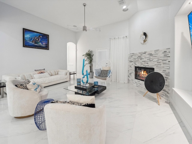 living room featuring ceiling fan and a tiled fireplace