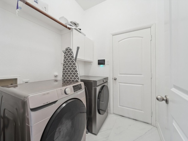 clothes washing area featuring cabinets and washer and dryer