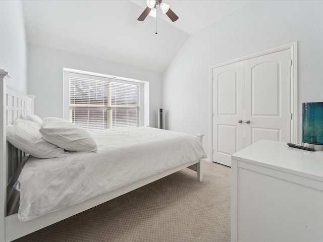 carpeted bedroom with ceiling fan, vaulted ceiling, and a closet