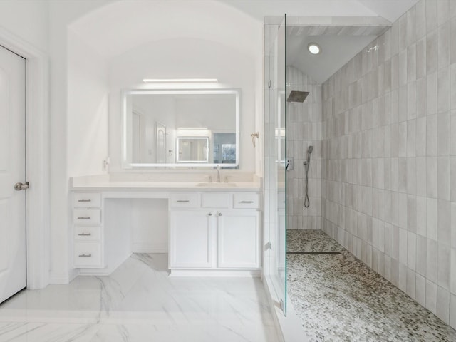 bathroom featuring a tile shower, vanity, and lofted ceiling