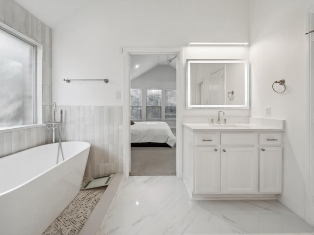 bathroom featuring vanity, a bath, vaulted ceiling, and tile walls