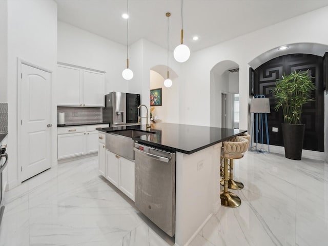 kitchen with white cabinetry, sink, hanging light fixtures, a kitchen island with sink, and stainless steel appliances