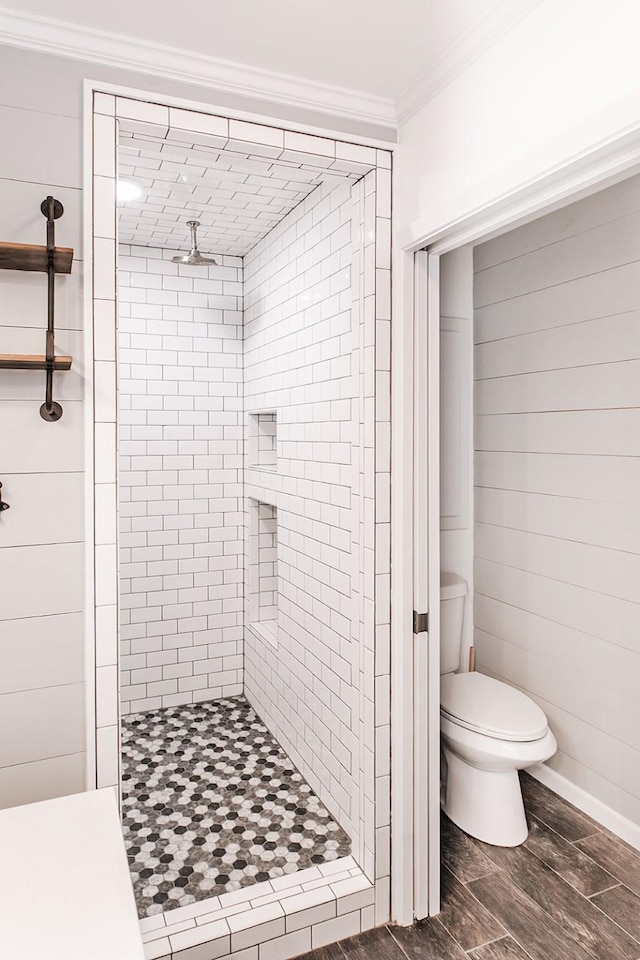 bathroom with a tile shower, crown molding, and toilet