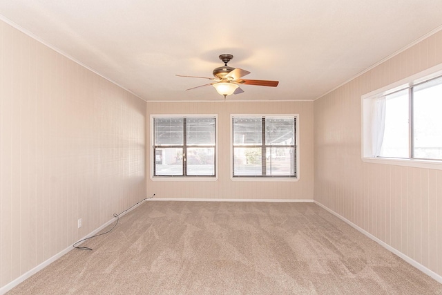 spare room featuring ceiling fan, crown molding, and light colored carpet