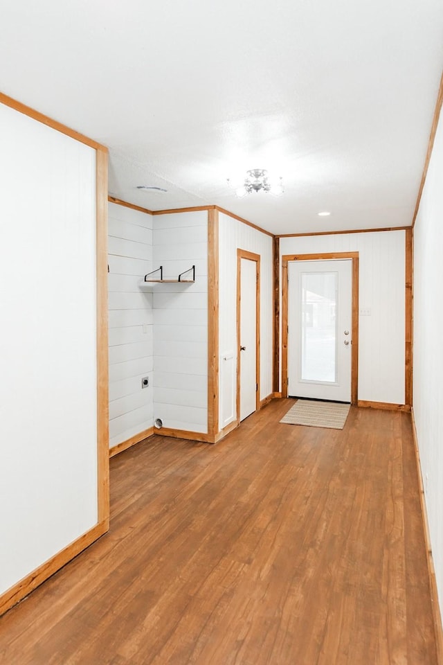 unfurnished room featuring wood walls, hardwood / wood-style floors, and ornamental molding