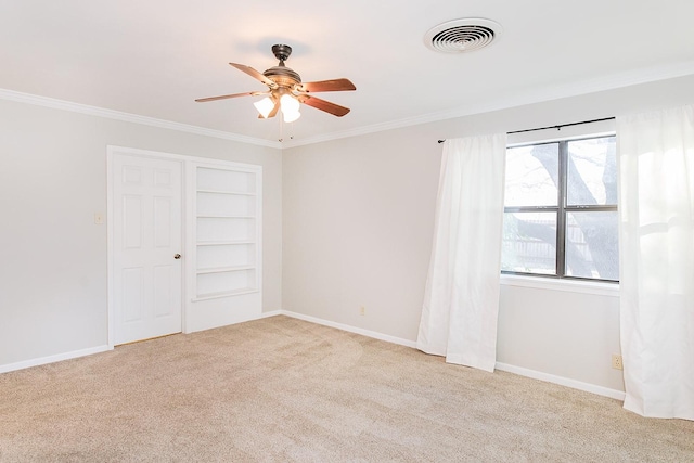 unfurnished room with built in shelves, light colored carpet, plenty of natural light, and ceiling fan