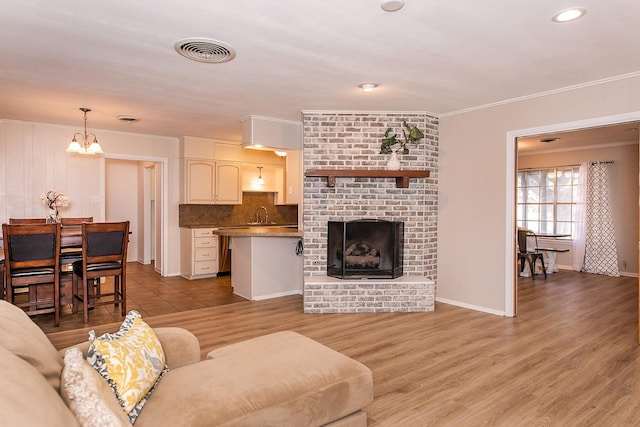 living room featuring sink, crown molding, a fireplace, and light hardwood / wood-style floors