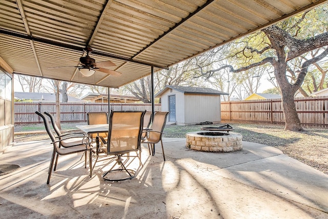 view of patio / terrace with a fire pit, ceiling fan, and a storage shed