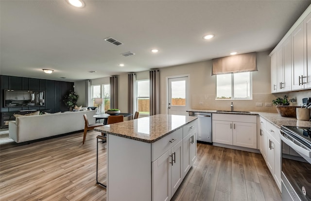 kitchen with stainless steel appliances, sink, a kitchen island, and white cabinets