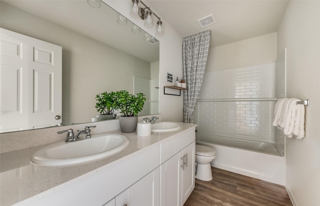 full bathroom featuring wood-type flooring, tiled shower / bath, vanity, and toilet