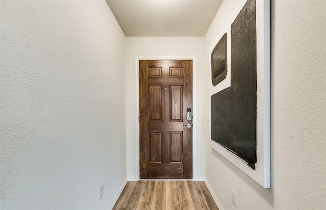 entryway with light hardwood / wood-style floors and a textured ceiling