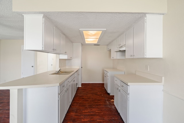 kitchen with kitchen peninsula, white cabinetry, sink, and dark wood-type flooring