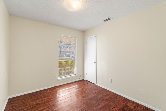 unfurnished room with dark hardwood / wood-style floors and a textured ceiling