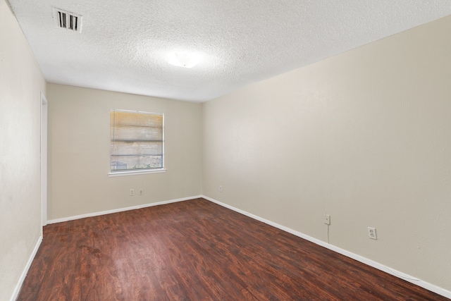 spare room featuring dark wood-type flooring and a textured ceiling