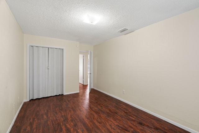 unfurnished bedroom featuring dark hardwood / wood-style flooring, a closet, and a textured ceiling