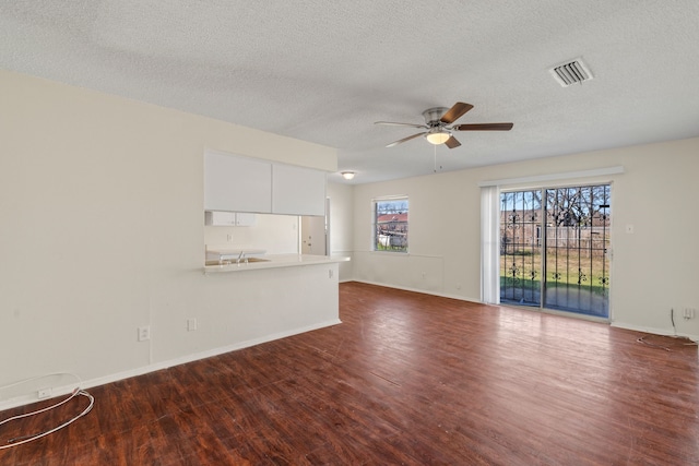 unfurnished living room featuring a textured ceiling, dark hardwood / wood-style floors, and ceiling fan