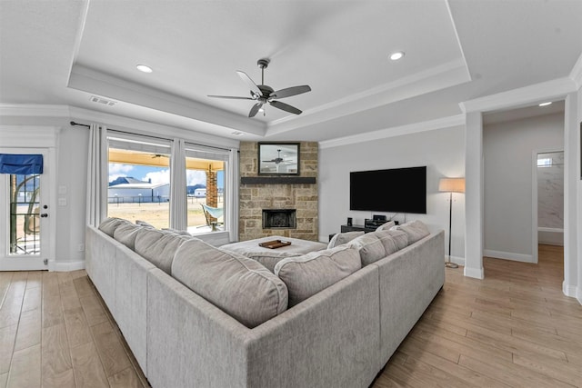 living room featuring light hardwood / wood-style floors, a fireplace, and a tray ceiling